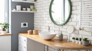 Cozy white bathroom with brick wall and wooden counter. Scandina